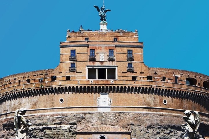 Castle with a statue on top against a clear blue sky