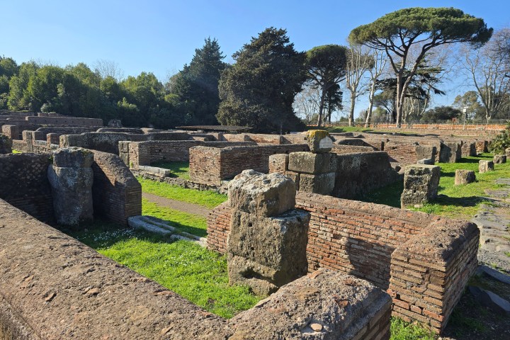 Ancient brick ruins surrounded by greenery and trees under a clear blue sky.