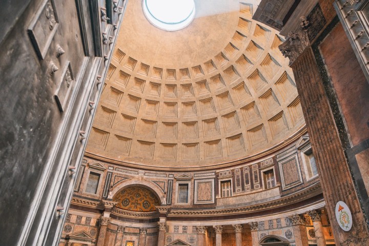 Interior view of a domed ceiling with an oculus and ornate decorations.