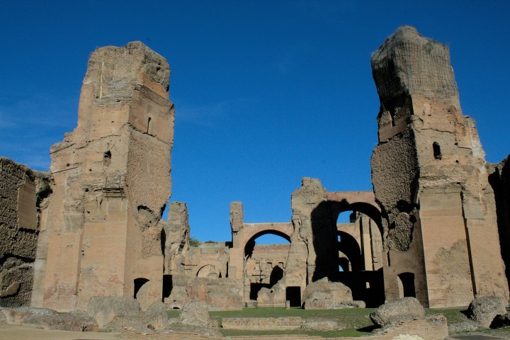 Ancient brick ruins with tall arches under a clear blue sky.