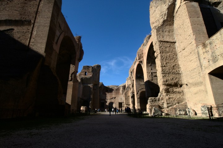 Ancient stone ruins with tall arches and blue sky.